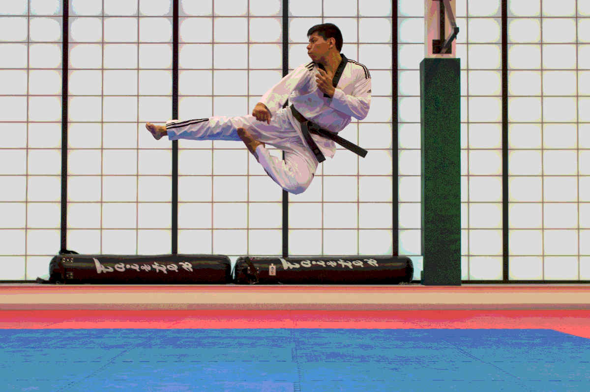 A man performs a flying kick high in the air